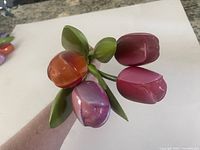 Four hand painted wooden tulips held together, showing the colors and leaves