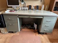 Full frontal view of vintage metal desk showing white laminate top and six drawers, three on each side.
