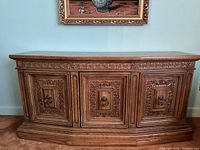 Front view of wooden cabinet showing three carved panels and smooth top surface