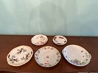 Five porcelain plates arranged on a wooden surface in a single photo showing size and variety.