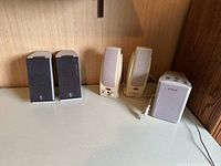 Photo showing three pairs of speakers on a shelf; includes Logitech desktop speakers, beige computer speakers, and Sony subwoofer.