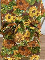 Tablecloth draped showing colorful orange, yellow, green flower pattern close up detail.