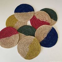 Top view of all 8 coasters arranged in a circle showing the half cream, half colored pattern in blue, green, red, mustard.
