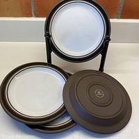 Set includes three vintage Hornsea Lancaster Vitramic contrast plates. Two plates stacked with underside and edges visible; one plate displayed showing front surface on a stand.