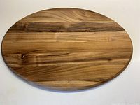 Full view of the wooden oval charcuterie/cutting board showing its shape and wood grain.
