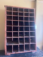 Front view of the antique wooden cubby hole cabinet showing multiple compartments and red paint.