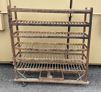 Front view of the antique wooden factory shoe rack showing multiple slatted shelves and mounted wheels.