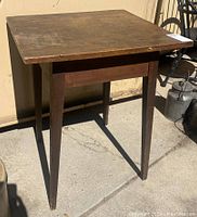 Side view of the antique pegged side table showing tapered legs and pegged construction with aged wood surface.