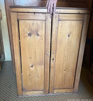 Front view of closed pine cupboard showing two paneled doors and top trim