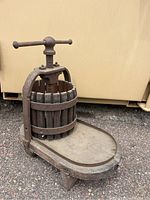 Front side angled view showing the screw handle, wooden slat basket, and wood base with juice collection tray.