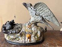 Front view of cast iron bank showing perched bird and nest with chicks