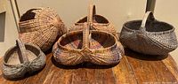 Five handcrafted woven baskets arranged together on a wooden surface.