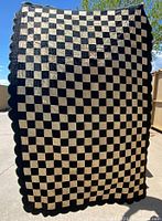 Full front view of the black and white checkerboard quilt showing the overall pattern and scalloped edges.