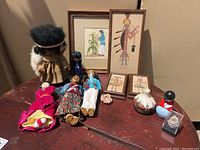 Overview photo displaying all items in the collection arranged on a table including framed Southwestern prints, cloth figurines, pottery, and a brooch.