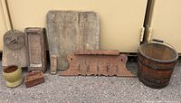 Photo of all antique wooden items including cutting board, game rack, barrel bucket, washboard, carved panel, small box, and bowl