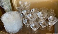 Photo of stacked clear Heisey rose etched plates and multiple stemmed glasses with rose etching detail.