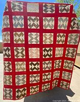 Full view of the quilt showing overall block pattern and red sashing with neutral patterned blocks.