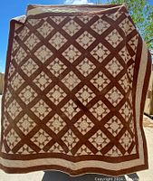 Full view of the brown and cream patchwork quilt showing the overall pattern and color scheme.