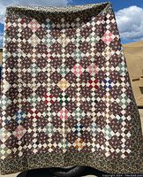 Full view of the vintage patchwork quilt showing multicolored squares and border fabric.