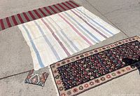 Three rugs displayed on concrete, showing the varying sizes, colors, and patterns.