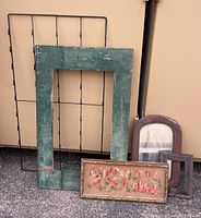 Full lot view including green painted wooden frame, black wire postcard holder, framed needlework, and other wooden frames.