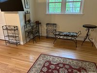 Full view of all items arranged along wall: small bookshelf, vanity with mirror and padded bench, hamper, and round side table.