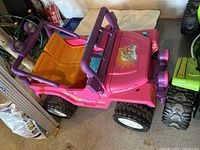 Pink children's ride-on toy car with purple frame and orange seat, detailed view from above