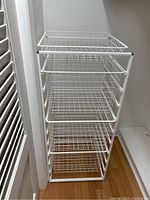 Photo of a white metal wire rack with six pull-out wire drawers for closet storage.