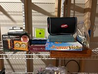 Full view of all games and chess clock on shelf, showing the boxed games and chess clock with carrying case.
