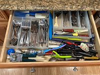 Drawer with organized cutlery on left and assorted kitchen utensils on right and front