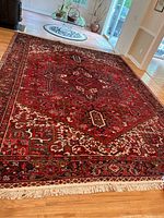 Full view of red Persian rug laid out on hardwood floor showing overall pattern and condition