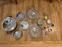 Top-down view of all silver and glass items arranged on floor, showing variety of bowls, trays, and other pieces.