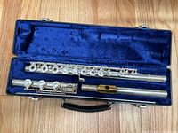Flute disassembled into three pieces laid in blue velvet-lined case