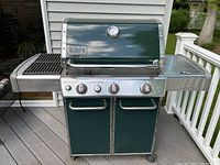 Front view of intact Weber Genesis grill showing dark green lid, temperature gauge, stainless steel control panel with three burner knobs and two lower cabinet doors