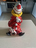 Front angle showing red clown costume, guitar held at side, and black shoes.