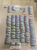 Full table view showing over 200 sheets of new NFL fingernail tattoos arranged in rows. Each sheet packaged with multiple small fingernail tattoos featuring NFL team logos.