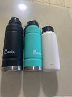 Front view of three stainless steel water bottles with logos visible: two Bubba and one Simple Modern.