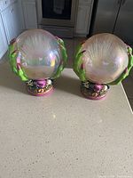 Pair of Halloween light-up globes on kitchen counter showing clear globes held by green claws and decorated bases