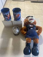 Two unopened 2013 Harley Davidson coffee mugs on a countertop with original packaging, accompanied by a plush toy and a covered ornament.