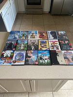 Full overview of 22 DVDs displayed on kitchen counter showing a variety of movie titles and genres
