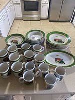 Full set of dishes and mugs arranged on kitchen counter, showing quantity and condition.