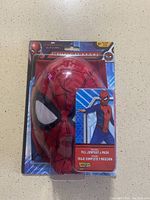 Front view of Spider-Man character mask inside clear plastic packaging with cardboard backing showing Marvel Spider-Man branding.