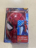 Front view of Spider-Man red mask in original plastic packaging with Spider-Man branding and age recommendation 4-6.