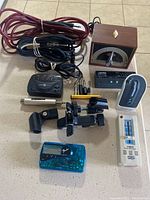 Full lot with cables in top left, Sabine metronome bottom right, Fender tuner bottom center, black clamps and small devices placed in center and right