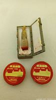 Carved stone seal stamp inside decorative storage box alongside two red ink pads.