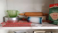 Mixing bowls, measuring cup, rolling pins, red rack, and coffee filters displayed on shelf