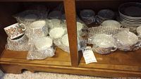 Various Cepelia cups and saucers wrapped in bubble wrap on shelf.