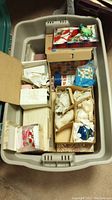 Overview photo of plastic storage bin filled with several smaller boxes containing Christmas ornaments wrapped in tissue paper.