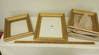 Three gold picture frames shown on table next to 36-inch ruler for scale, details the variety in sizes and styles in lot.