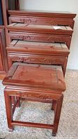 Four stacked wooden nesting tables showing sizes and carved decorative apron detail.